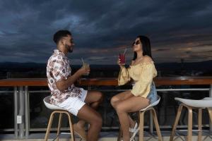 un homme et une femme assis sur un balcon avec des boissons dans l'établissement Rio Cumbaza Hotel, à Tarapoto