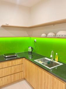a green wall in a kitchen with a sink at Quân's homestay in Ho Chi Minh City