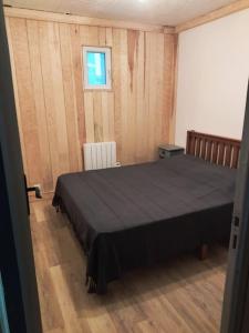 een slaapkamer met een zwart bed en een raam bij Petit nid au coeur des pins ! in Matemale