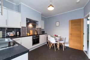 a kitchen with white cabinets and a table and chairs at Newly Renovated Perfect Family Home in Nottingham in Nottingham