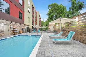 a swimming pool with chairs and an umbrella next to a building at Home2 Suites By Hilton Asheville Biltmore Village in Asheville