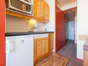 a kitchen with wooden cabinets and a white dishwasher at Studio Avoriaz, 1 pièce, 4 personnes - FR-1-314-219 in Morzine