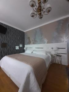 a bedroom with a white bed and a chandelier at A Flor da Rosa in Vila Nova de Foz Coa