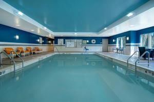 a swimming pool with orange chairs in a blue room at Hampton Inn & Suites Yonkers in Yonkers