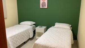 two beds in a room with a green wall at Pousada Jaguary in Bragança Paulista