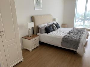 een slaapkamer met een bed en een nachtkastje met een lamp bij Bracknell Stunning 2 Bedroom and 2 Bathroom Apartment in Bracknell