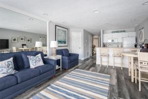a living room with a blue couch and a kitchen at Beachside 213 with Pool Hot Tub and Private Deck overlooking East Bay in Traverse City