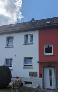 a white and red house with a door at FeWo Schellenbergstraße in Kißlegg +5 photos