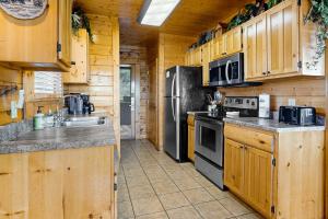 a kitchen with wooden cabinets and appliances in a cabin at A Walk in the Clouds in Pigeon Forge