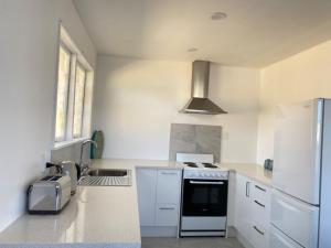 a white kitchen with a stove and a sink at Ali Motel in Auckland
