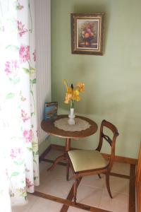 une table avec un vase de fleurs et une chaise dans l'établissement Maison d'Hotes du Vert Vallon, à Theizé