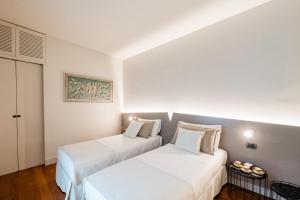 twee bedden in een kamer met witte muren bij Airport BEA Rooms in Azzano San Paolo
