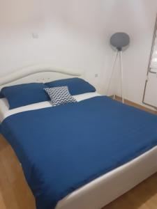 ein blaues Bett mit blauen Kissen im Schlafzimmer in der Unterkunft Garden- pool apartman 