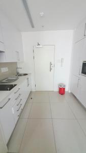 uma cozinha branca com armários brancos e um balde vermelho em iTowers Studio-Suite em Gaborone