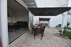 eine Terrasse mit einem Tisch, Stühlen und einem Sonnenschirm in der Unterkunft Casa Romeo in Lecce