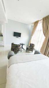 a bedroom with a bed and two chairs and a tv at iTowers Studio-Suite in Gaborone