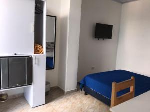 a bedroom with a blue bed and a tv at The Mendoza Grand Hotel in Barranquilla