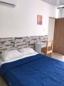 1 dormitorio con cama azul y escritorio en The Mendoza Grand Hotel, en Barranquilla