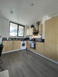 a large kitchen with wooden cabinets and a white dishwasher at Chertsey - Beautiful Modern 2 Bedroom Apartment in Chertsey