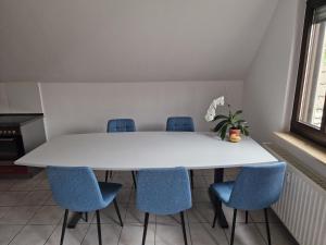 una mesa blanca con sillas azules en una habitación en Ferienwohnung Zentrum Luckau, en Luckau