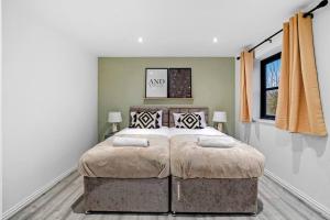 a bedroom with a large bed with two pillows at Luxury House with Pool Table, Sky TV, Netflix, Fast Wifi, Garden & Free Parking by Yoko Property in Milton Keynes