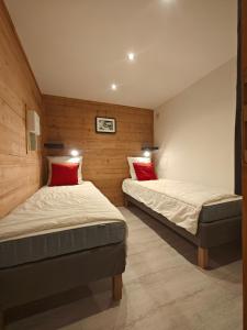 two beds in a room with wooden walls at Chez Carole et Arnaud in Val Thorens
