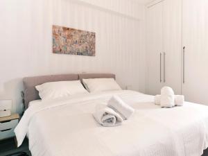 a white bedroom with two white towels on a bed at "Under the olive tree"- Beautiful apartment in the heart of Athens in Athens