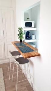 een keuken met een tafel met stoelen en een magnetron bij Le Chat Bleu - 26m2- Terrasse sur les toits - Wi-fi in Amiens