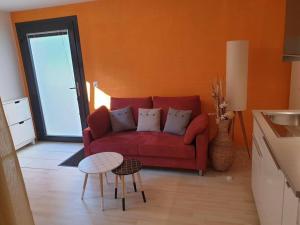 un soggiorno con divano rosso e tavolo di Studio agréable avec accès indépendant. a Yverdon-les-Bains