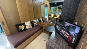 a living room with a couch and a flat screen tv at Tropical Pool, Balcony, MOA, Airport, Entire Apartment at Shell Residence in Manila