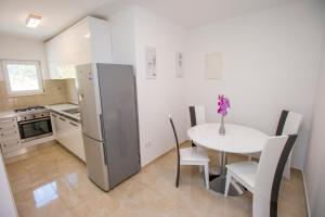 a kitchen with a white table and a refrigerator at APARTMAN KSENIJA KOVAČIĆ in Stanići