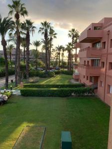 Una vista de un edificio con palmeras y un patio. en Charming 3 Bedroom apartment with sea view in the heart of Sotogrande, en Sotogrande