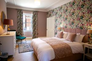 1 dormitorio con 1 cama grande y papel pintado con motivos florales en No 1 St George’s Terrace., en Carrick on Shannon