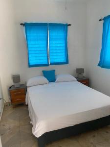 a bedroom with a large white bed with blue windows at Caribbean Domicile in Las Terrenas