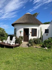 a small white house with a thatched roof at Rondawel with sea view in Kleinmond