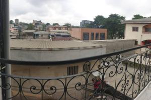 een vrouw op een balkon met uitzicht op een stad bij Le relax in Bonamoussadi