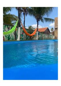 een zwembad met een hangmat en palmbomen bij Pousada HOME BEACH MAR porto das dunas BEACH PARK in Aquiraz