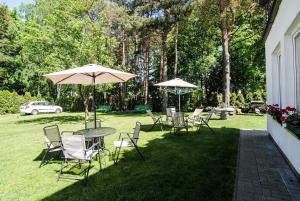 a group of chairs and tables with umbrellas on a lawn at Elena in Palanga