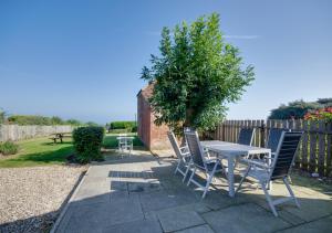 a patio with a table and chairs and a tree at East Dene in Overstrand