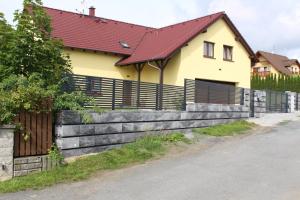 a yellow house with a wooden fence in front of it at Apartmán 2023 in Stříbro