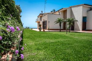 una casa con un patio con césped y flores en Villa Calliope Sea Beach, en Fontane Bianche