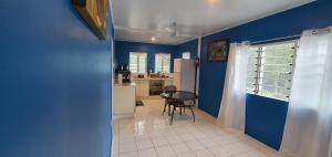 um quarto azul com uma mesa e uma cozinha em Lynn's Getaway Guest House em Apia