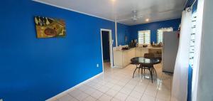 um quarto azul com uma mesa e uma cozinha em Lynn's Getaway Guest House em Apia