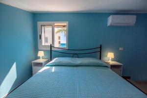 Dormitorio azul con cama y ventana en Villa Calliope Sea Beach, en Fontane Bianche