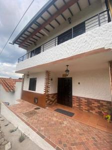 a white house with a black door and a brick patio at Casatoca House Zapatoca Lengerke in Zapatoca