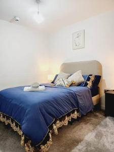 ein Bett mit einer blauen Decke und Kissen darauf in der Unterkunft Long term rental in Man City in Manchester