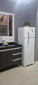 une cuisine avec un réfrigérateur blanc et une fenêtre dans l'établissement Casa Familiar Moradas Pelotas, à Pelotas
