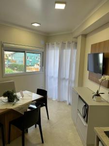 a living room with a table and a kitchen with a tv at Apartamento Completo Próximo a Praia - Residencial Vieira in Florianópolis