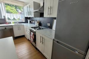 a kitchen with white cabinets and a stainless steel refrigerator at Antoni's Apartment in London