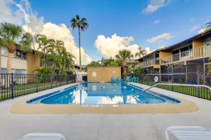 a swimming pool in the courtyard of a apartment building with palm trees at Welcoming Sarasota Vacation Rental with Pool! in Sarasota